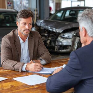 Young man at a table with an insurance agent after a car accident in Pennsylvania illustrating a case handled by Wilk Law Personal Injury & Car Accident Lawyers