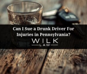 Empty shotglass on a wooden table in a bar with car keys next to it in Pennsylvania related to a drunk driver injury claim handled by Wilk Law Personal Injury & Car Accident Lawyers