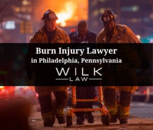 EMTs assisting burn victim with building on fire in background in Philadelphia, Pennsylvania