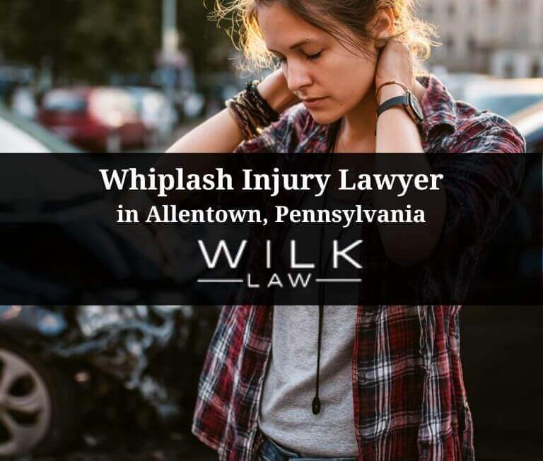 Woman with a whiplash injury standing next to her crashed car Allentown, Pennsylvania, related to a case handled by Wilk Law Personal Injury & Car Accident Lawyers