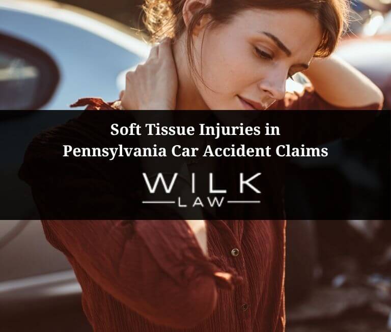 Woman next to her crashed car with her hand on the back of her neck to relieve the pain from soft tissue injuries in Pennsylvania